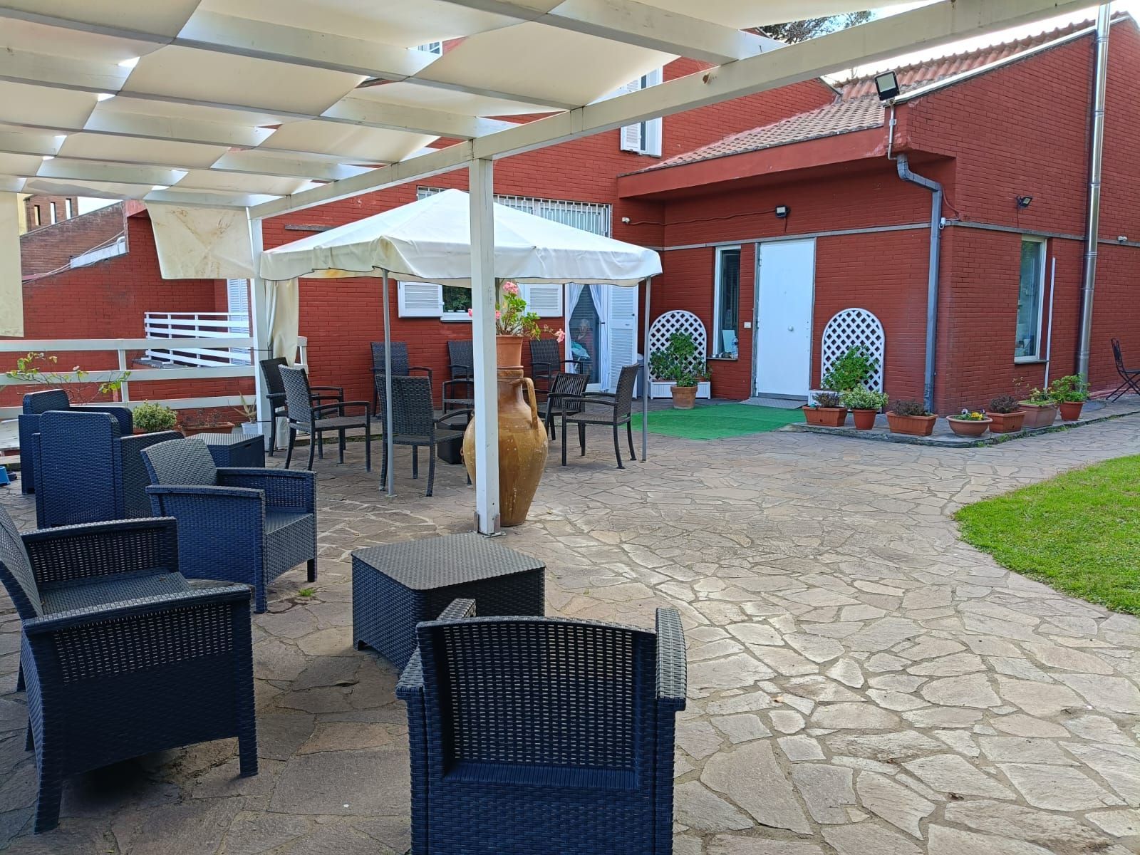 Un patio con sedie e un tavolo sotto un ombrellone