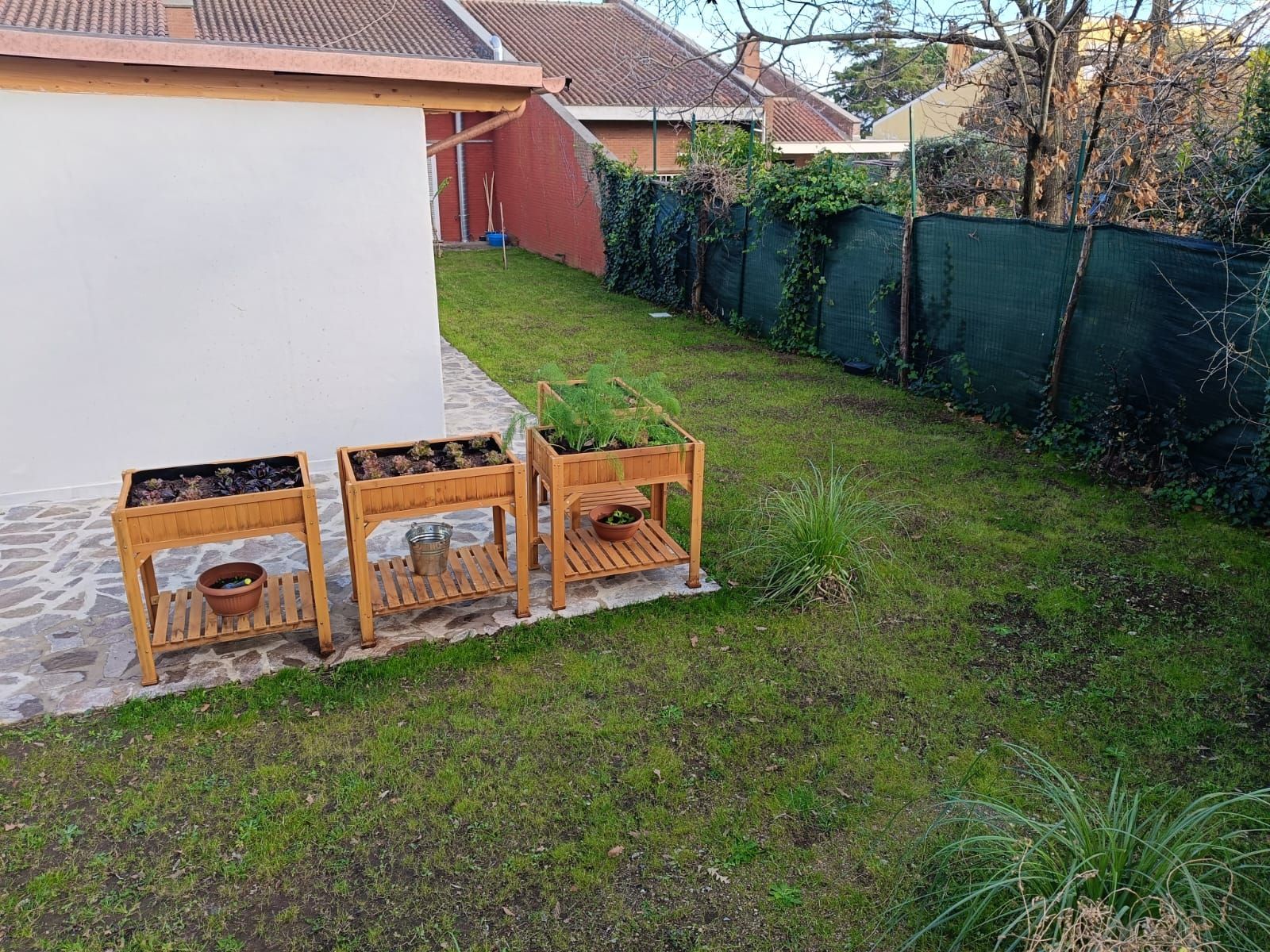 Ci sono tre fioriere di legno nel cortile di una casa.