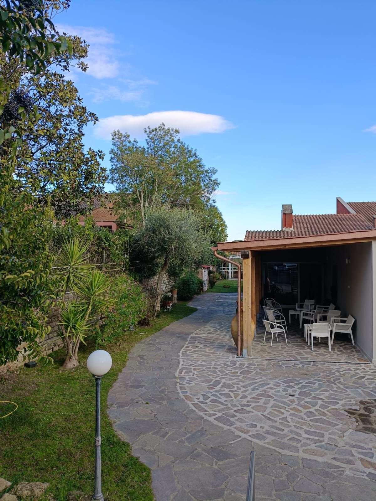 Un sentiero in pietra che conduce a una casa con tavoli e sedie.