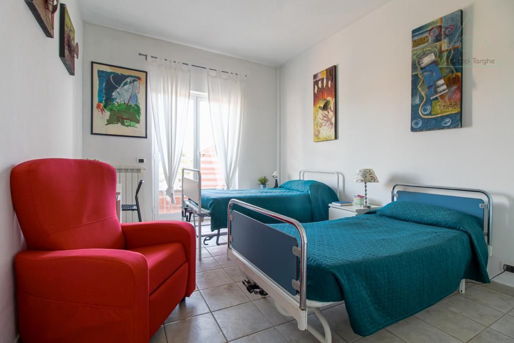Una camera da letto con due letti e una sedia rossa