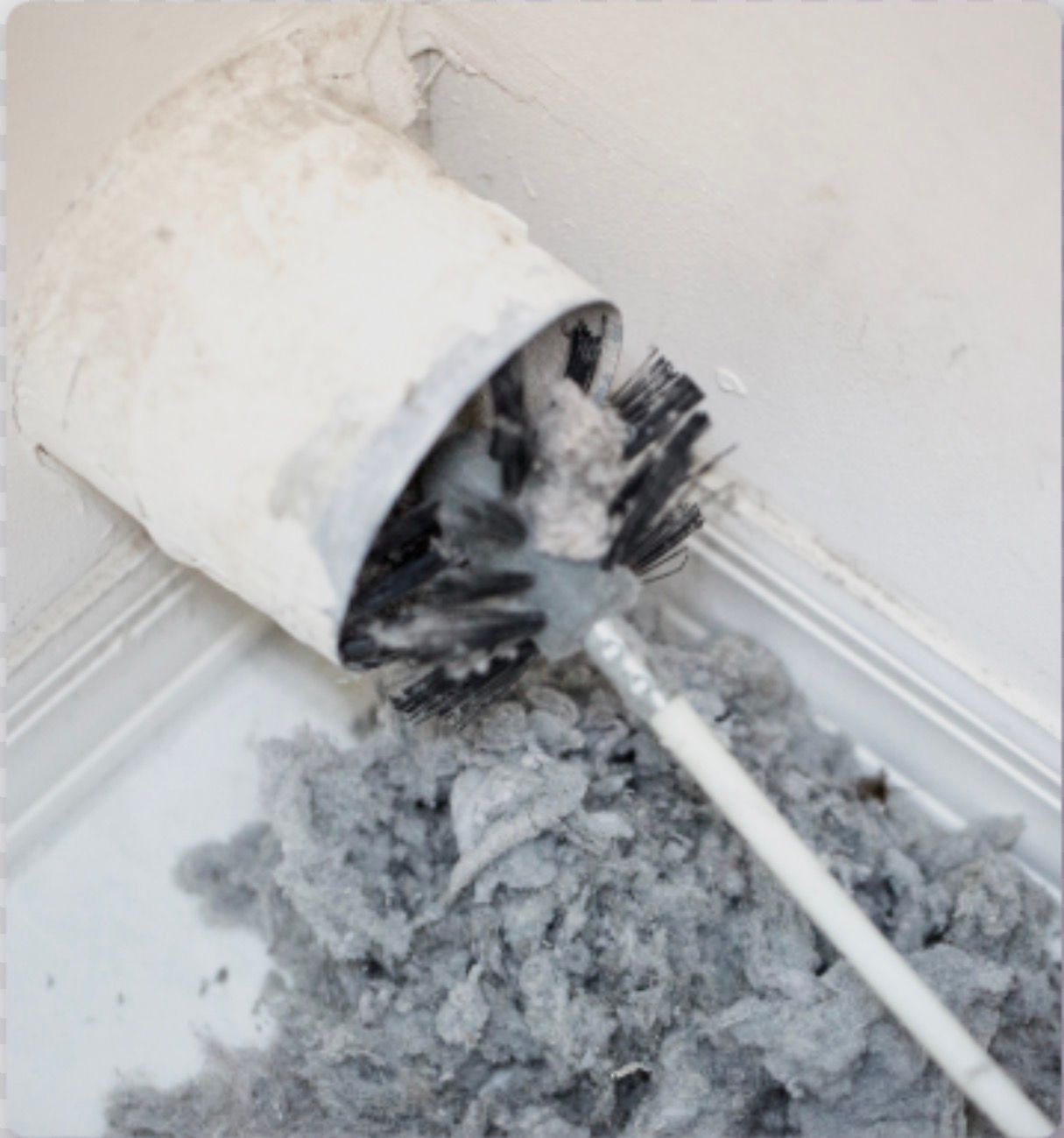 Brush cleaning lint out of a white dryer vent.