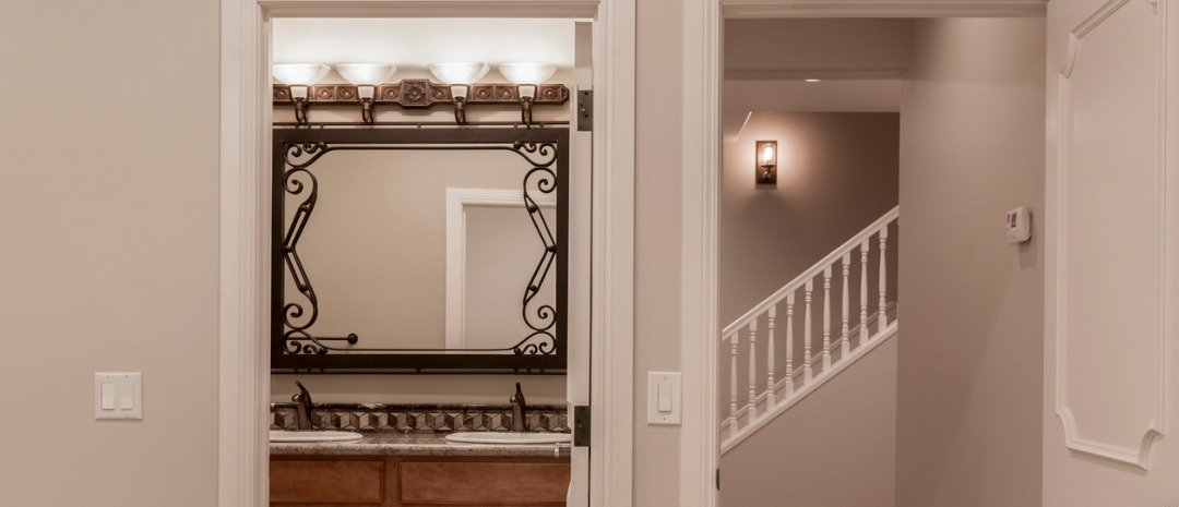 Hallway with a powder room and a staircase. Light beige walls.
