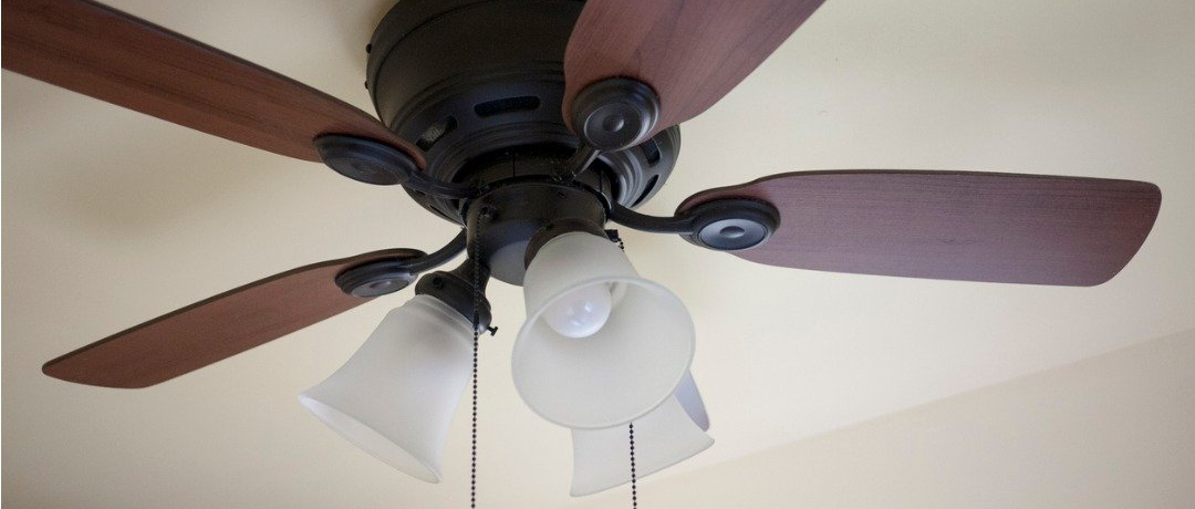 Ceiling fan with brown blades and white light fixtures.
