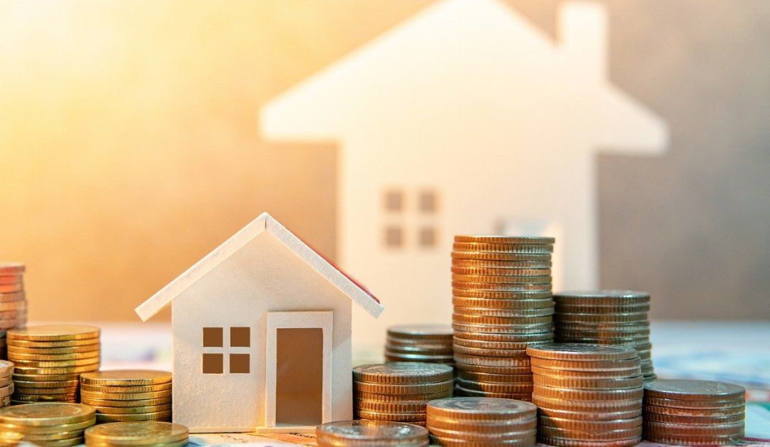 Miniature houses with stacks of coins, representing real estate investment.