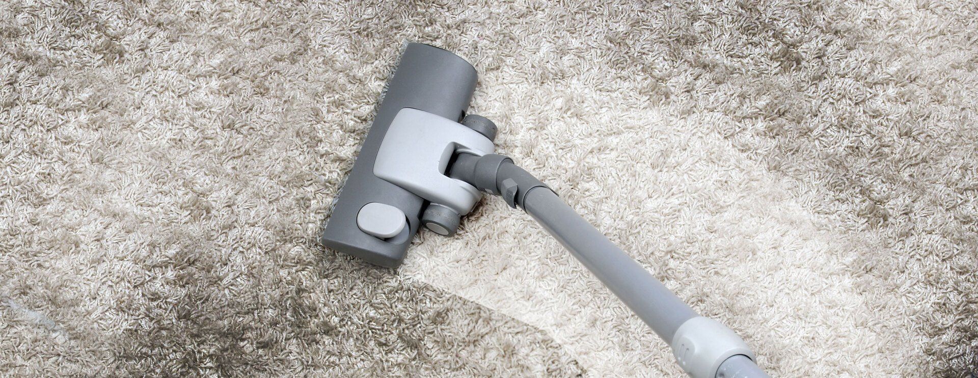 A vacuum cleaner is cleaning a carpet on the floor.