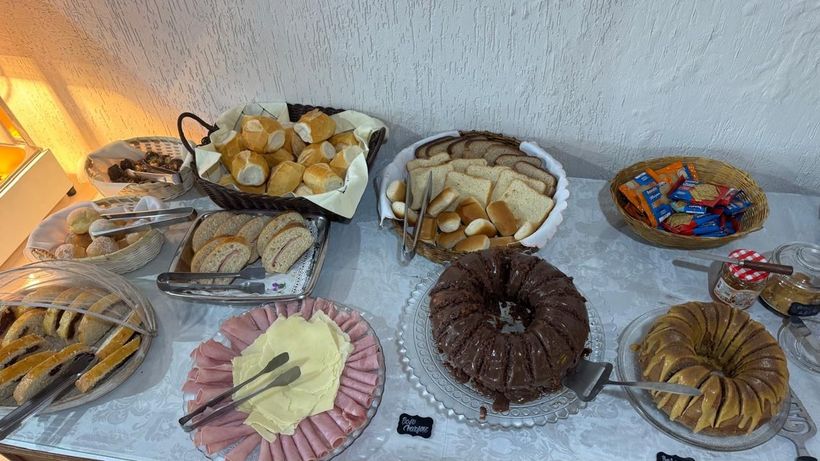 Doces e biscoitos variados dispostos em bandejas sobre uma mesa coberta com uma toalha de mesa branca.