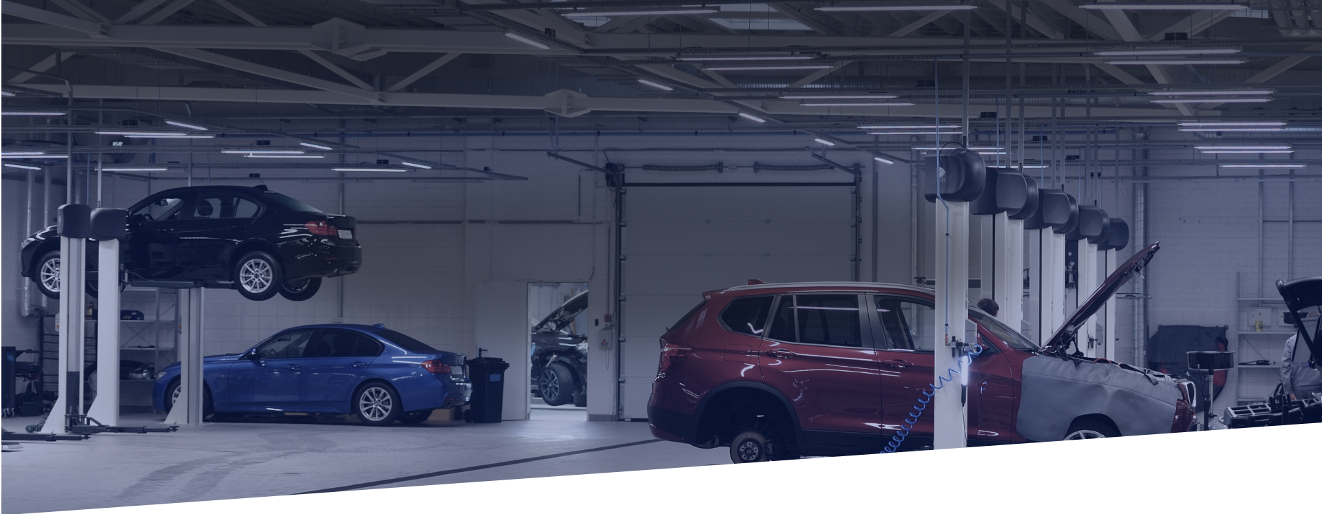 A row of cars are sitting on a lift in a garage. | Greatway Tire and Auto Center