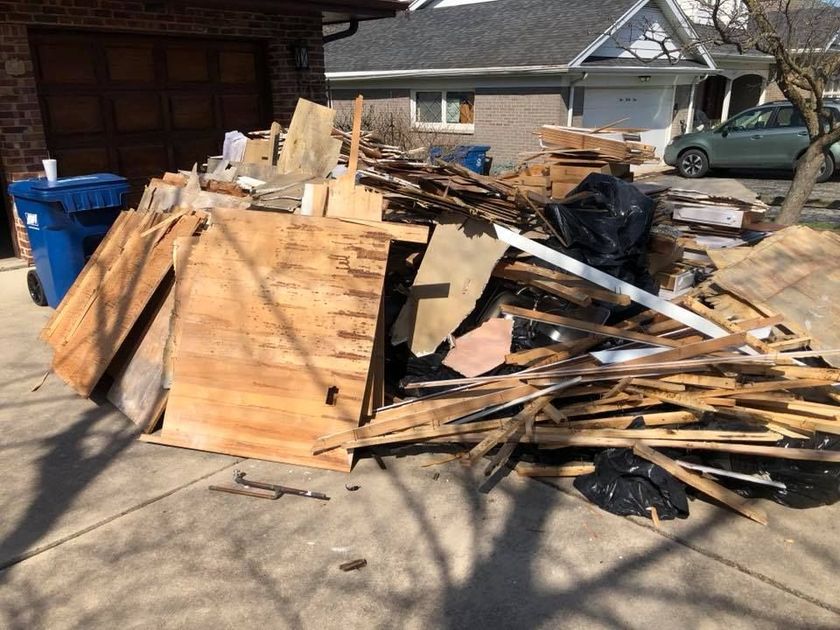 a pile of wood is sitting on the sidewalk in front of a house .