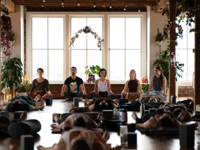 People seated in a bright yoga studio during a guided meditation class