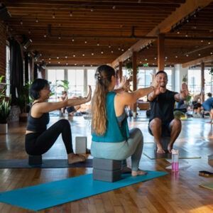 People doing yoga on blocks in a bright wooden studio