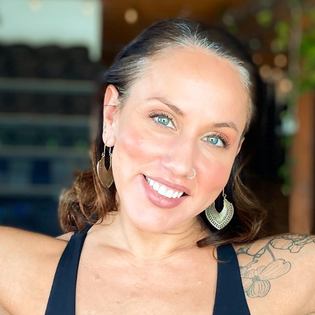 Smiling woman with blue eyes and hoop earrings, close-up portrait in a softly lit indoor setting