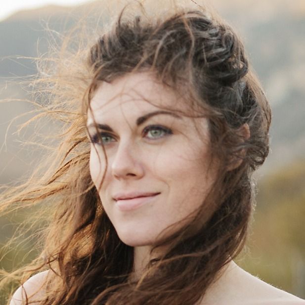 Woman with windblown hair looking off-camera in a natural outdoor setting