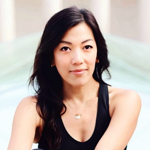 Portrait of a woman with long dark hair, wearing a black sleeveless top against a soft blurred background