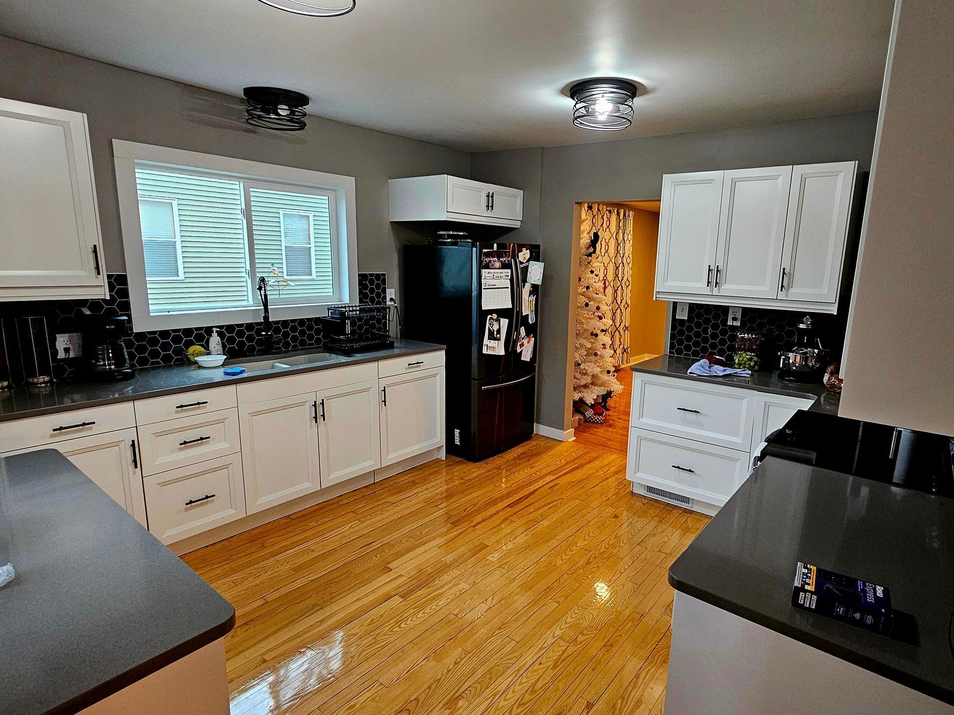 A kitchen with white cabinets and a black refrigerator