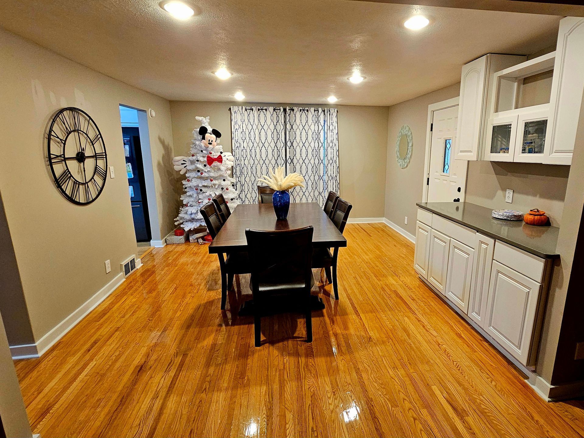 A dining room with a table and chairs and a clock on the wall