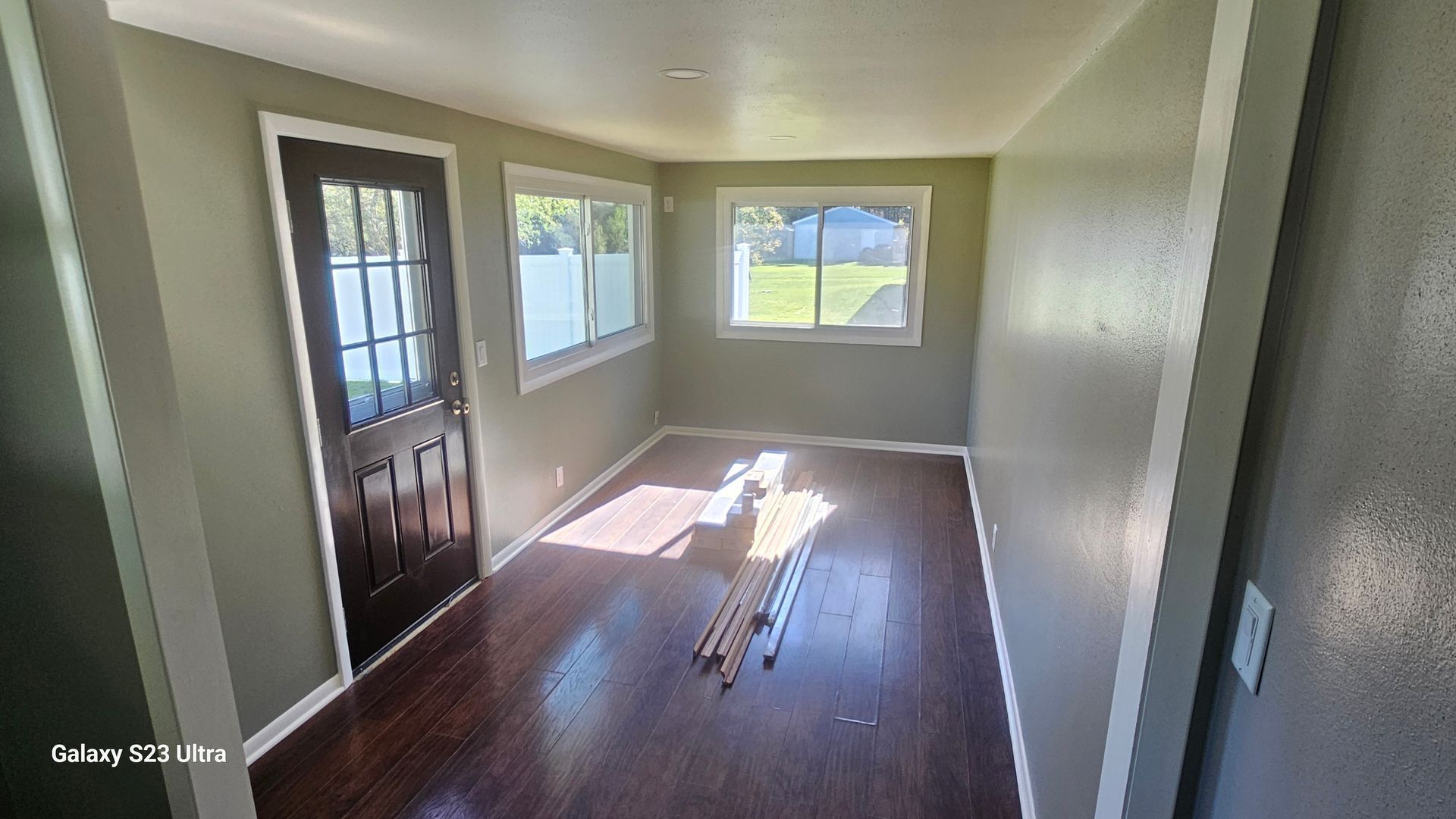An empty living room with hardwood floors and a black door