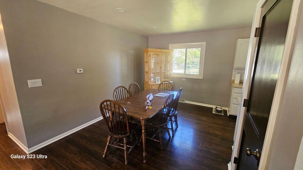A dining room with a table and chairs and a window.