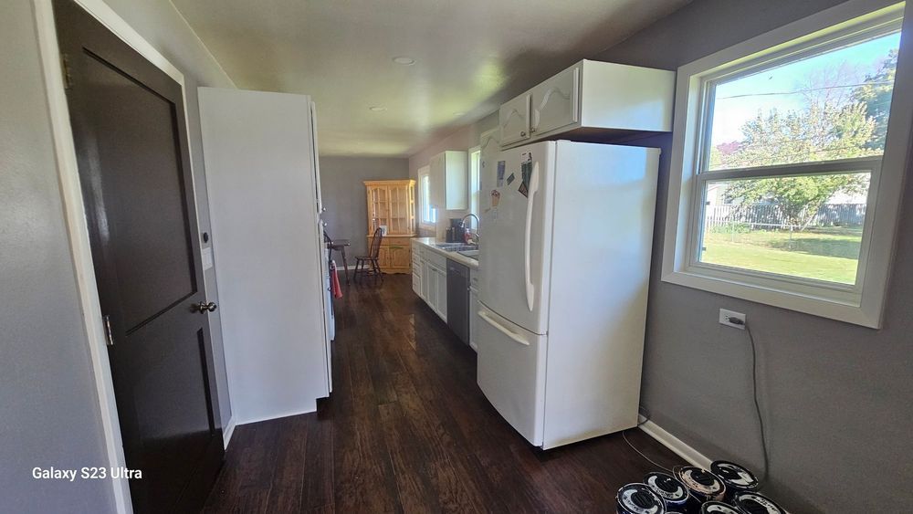 A long hallway in a house with a refrigerator and a window