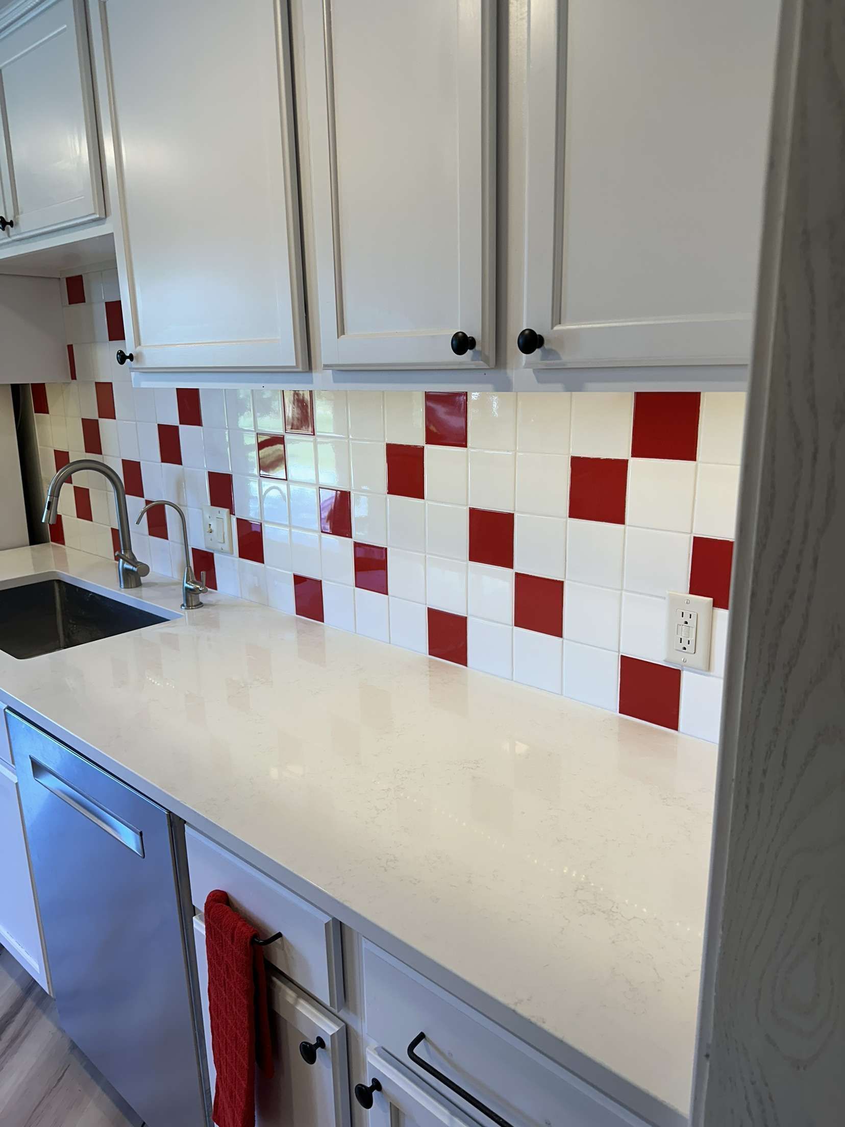 A kitchen with red and white tiles and white cabinets