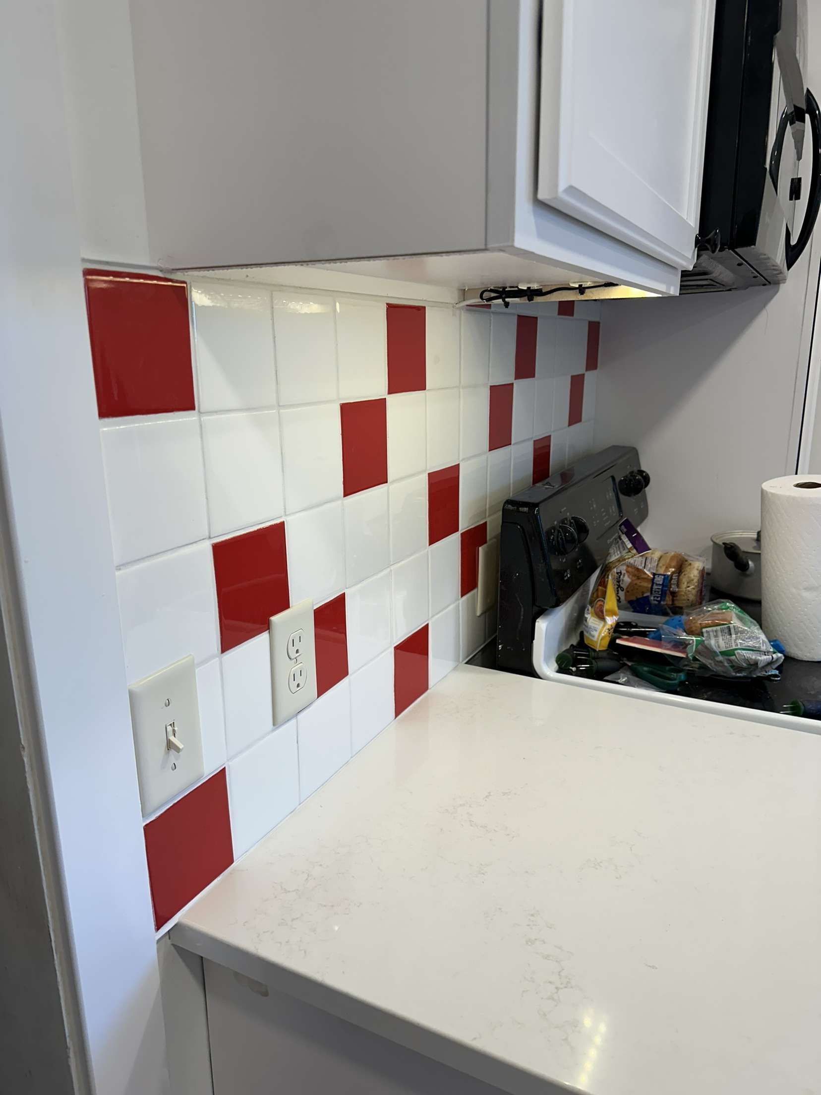A kitchen with red and white tiles on the wall