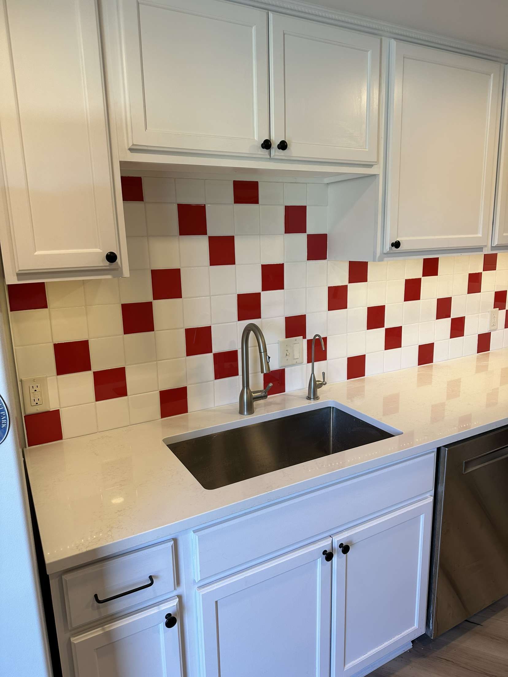 A kitchen with red and white tiles and a sink