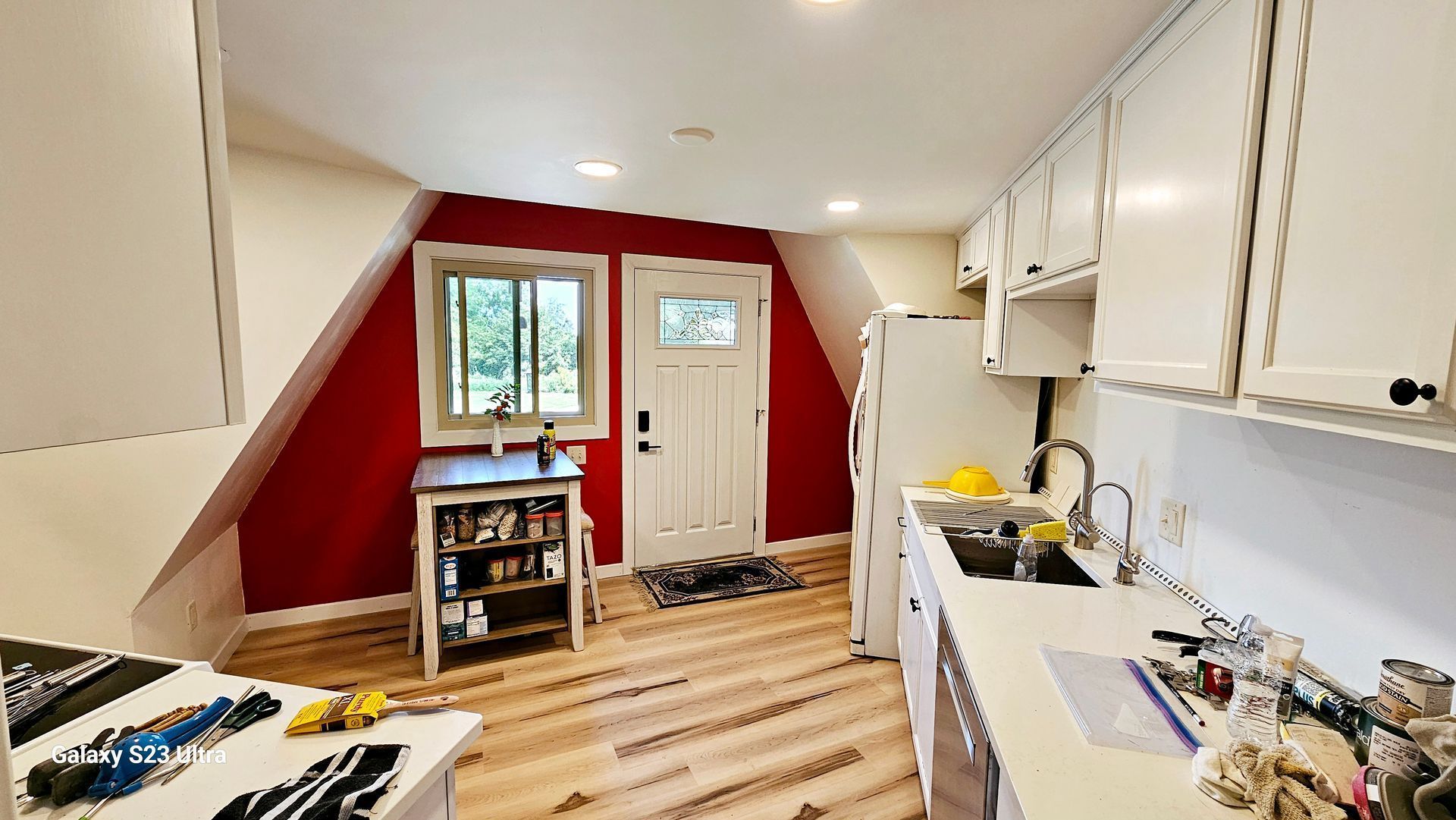 A kitchen with red walls and white cabinets and a door
