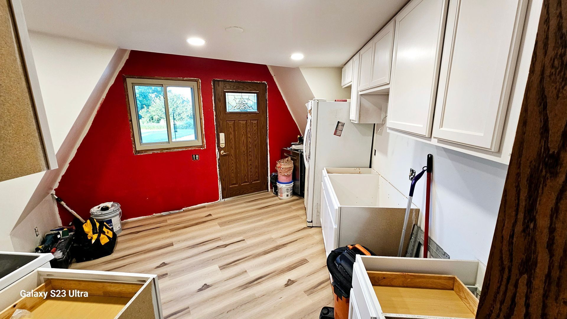A kitchen with red walls and white cabinets is being remodeled.