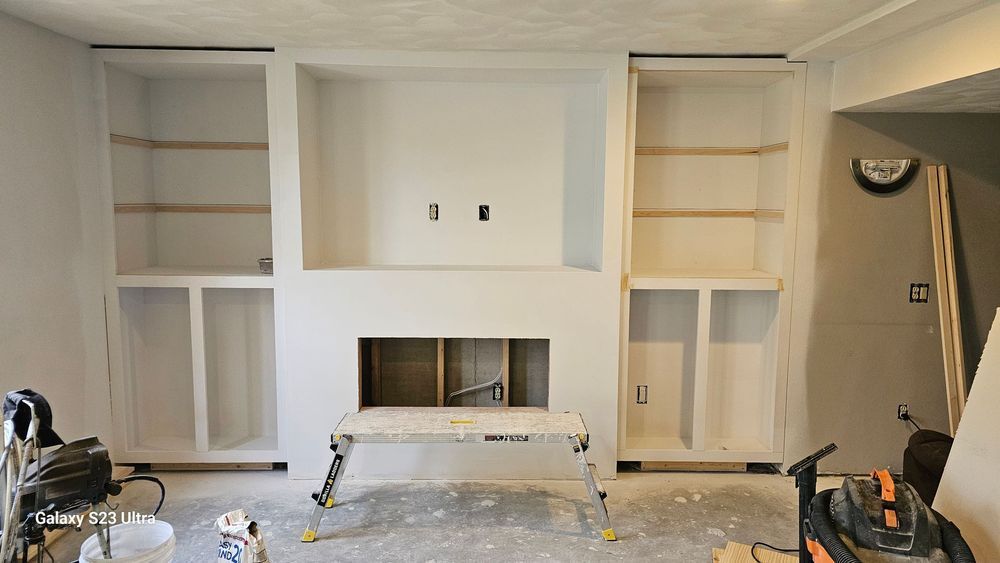 A living room with a fireplace and shelves being built
