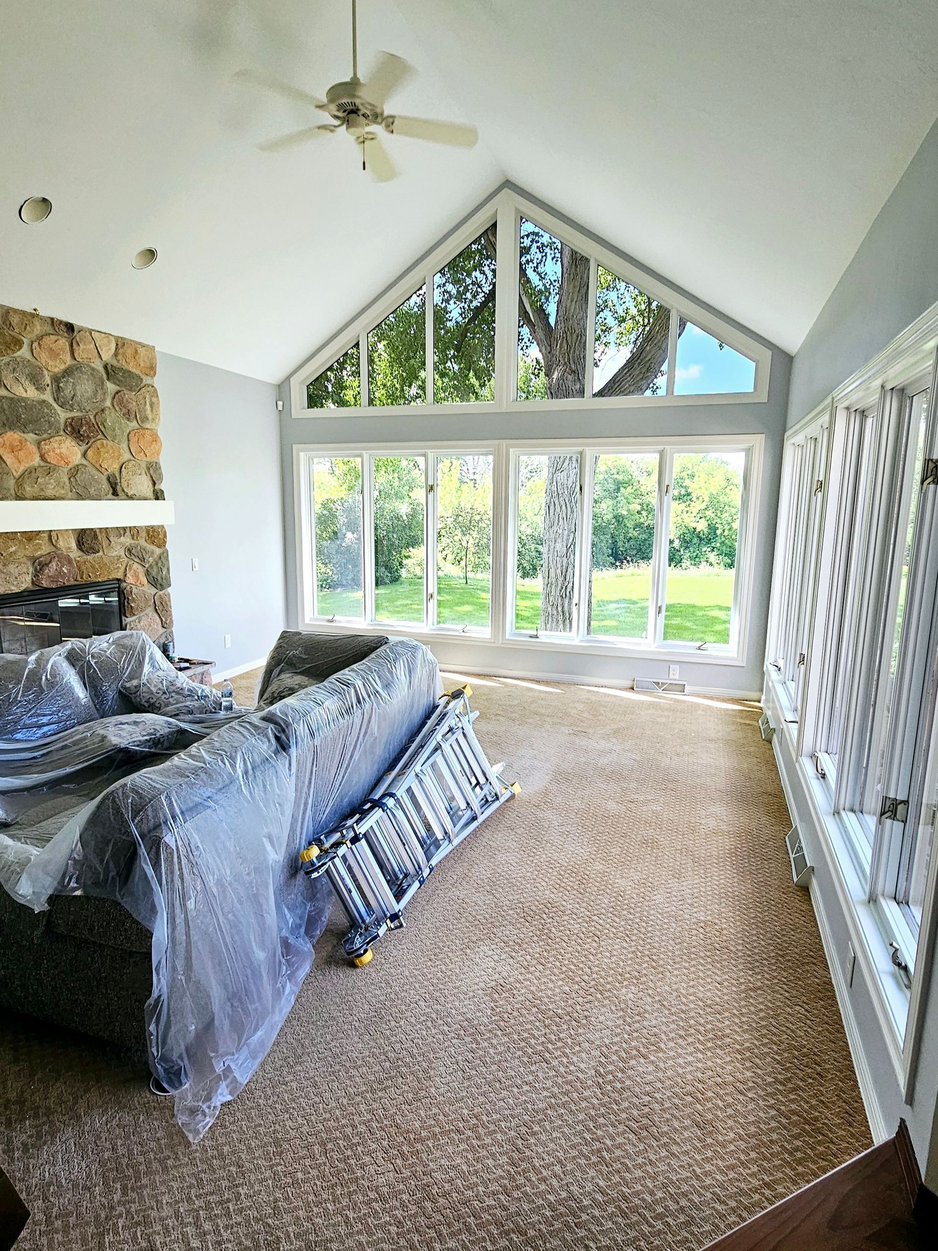 A living room with a couch covered in plastic and a ceiling fan