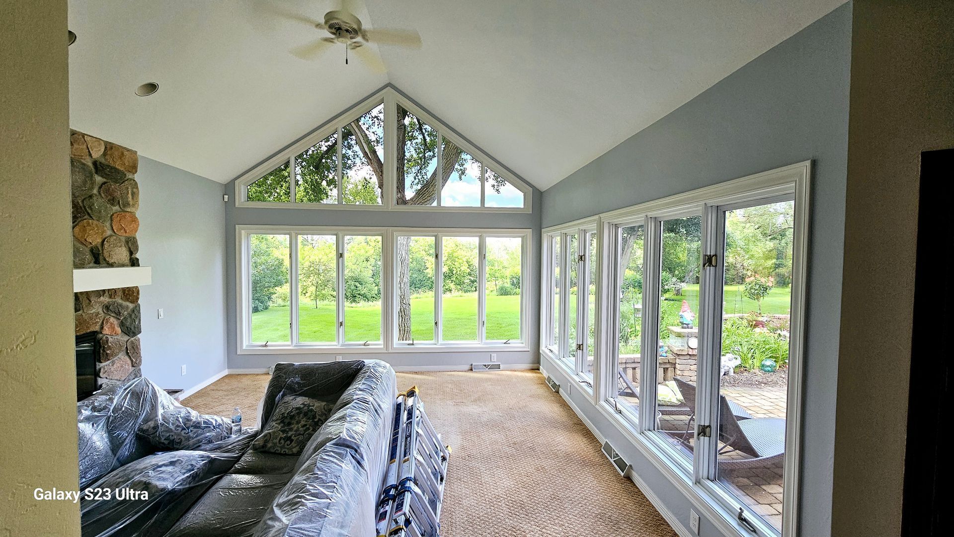 A living room with a lot of windows and a ceiling fan