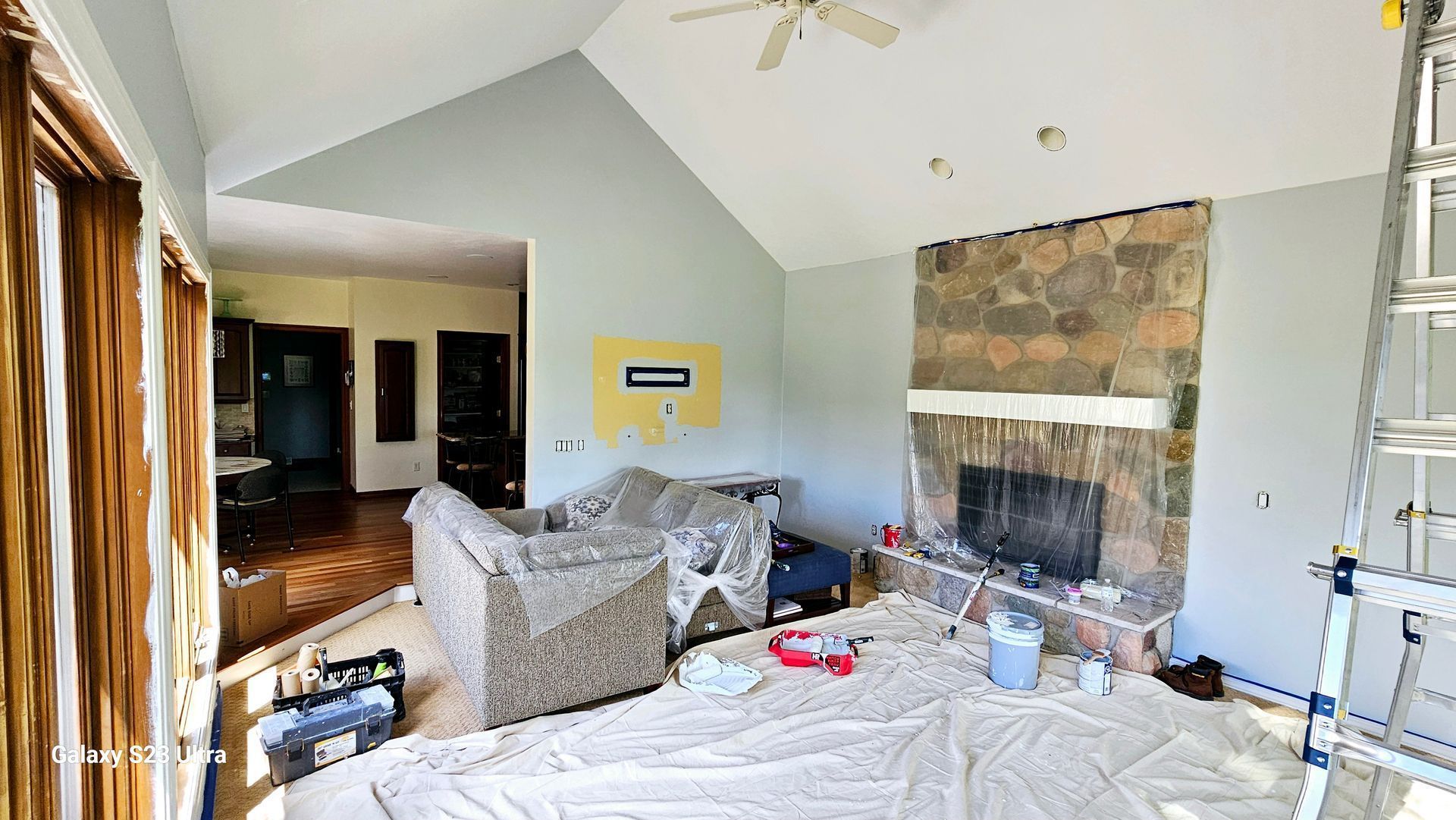 A living room with a fireplace and a couch being painted