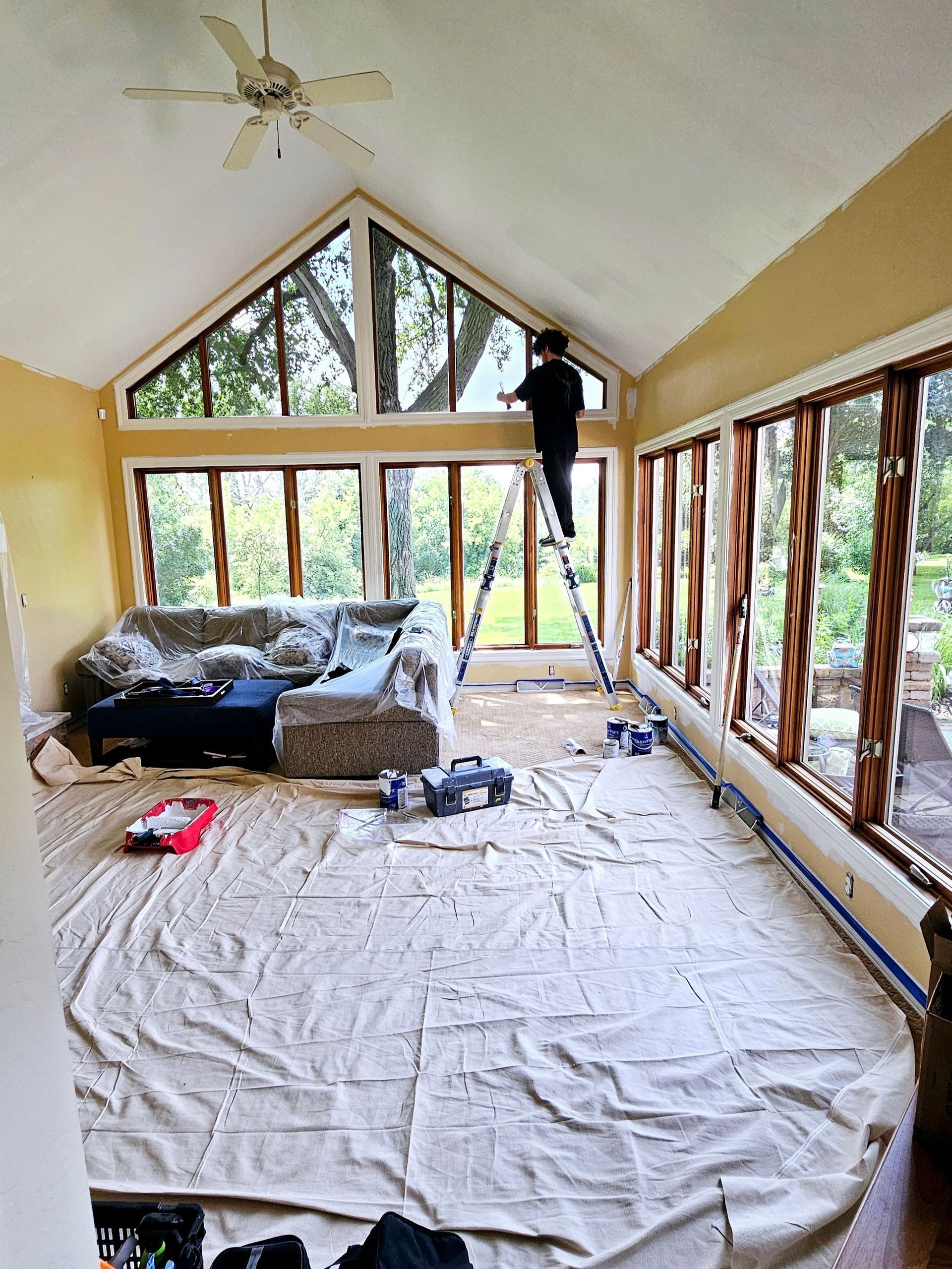 A man is standing on a ladder in a living room