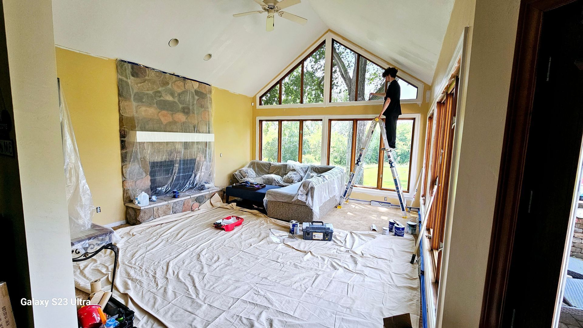 A man is standing on a ladder in a living room
