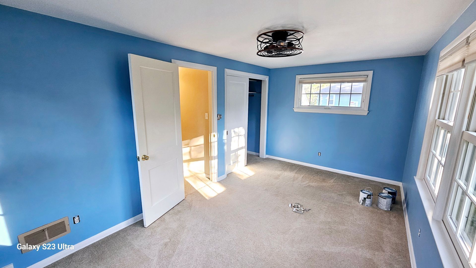An empty room with blue walls and white trim