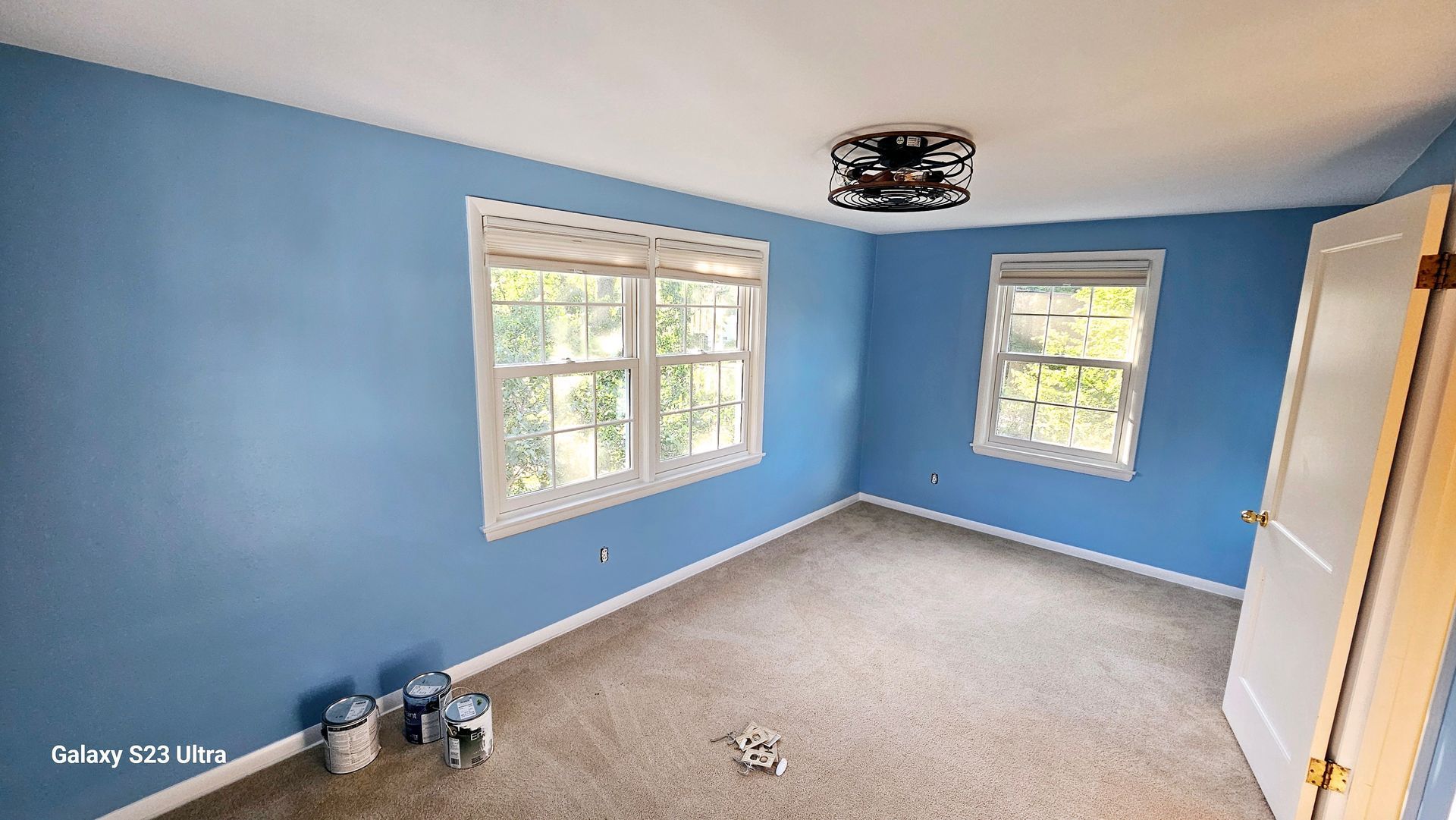 A room with blue walls and white trim is being painted