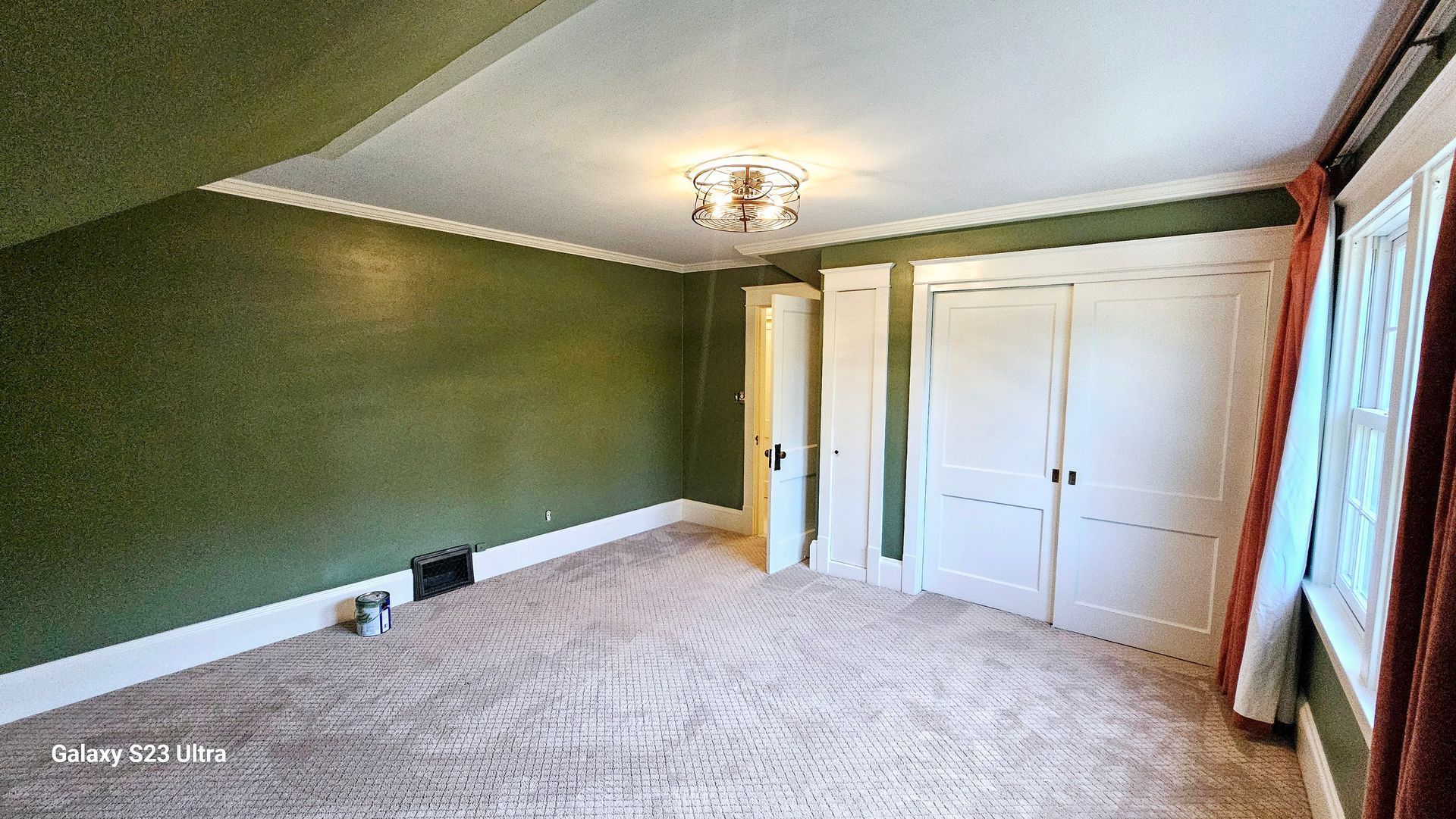 An empty room with green walls and a carpeted floor