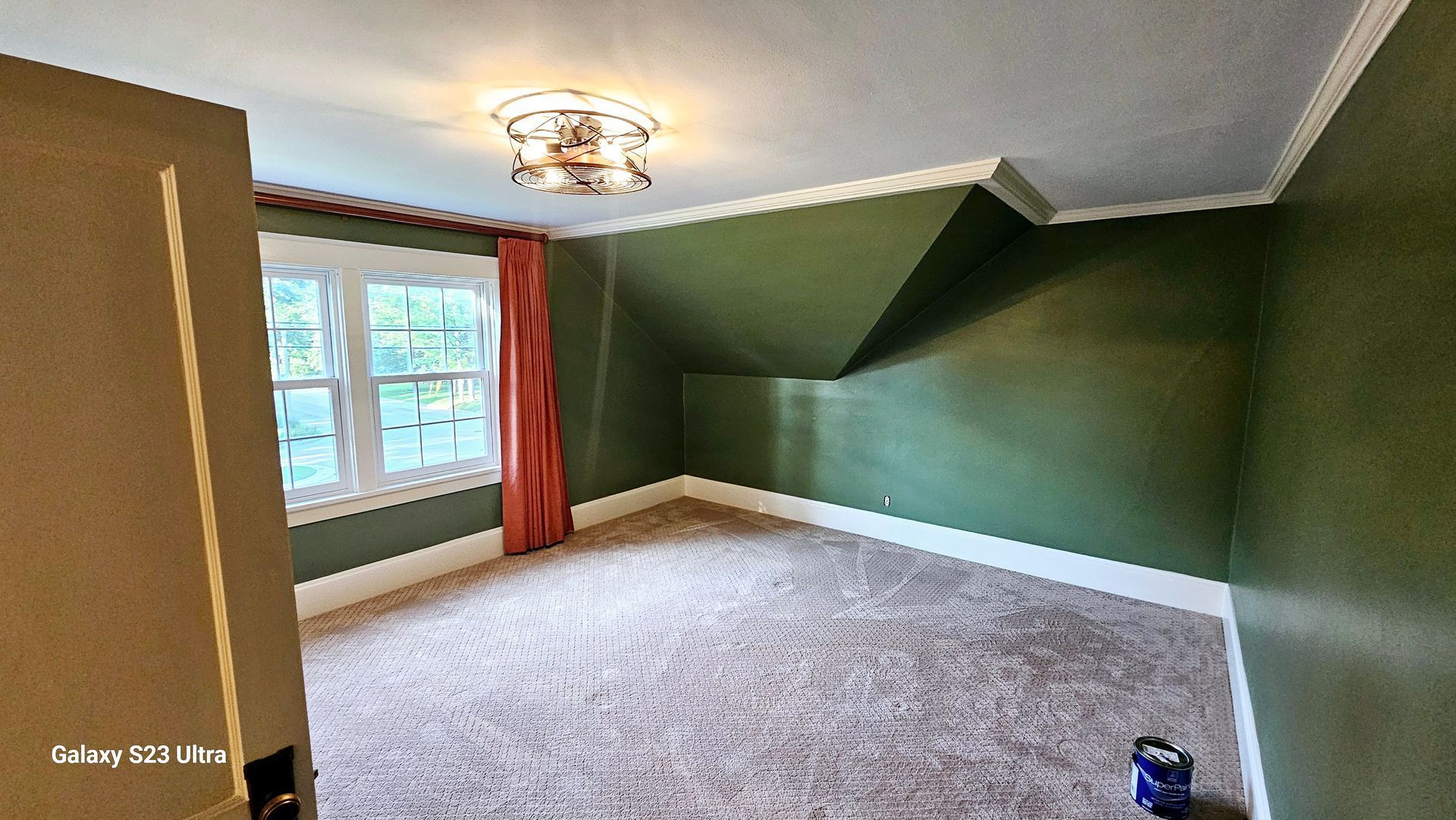 An empty room with green walls and a chandelier in the ceiling