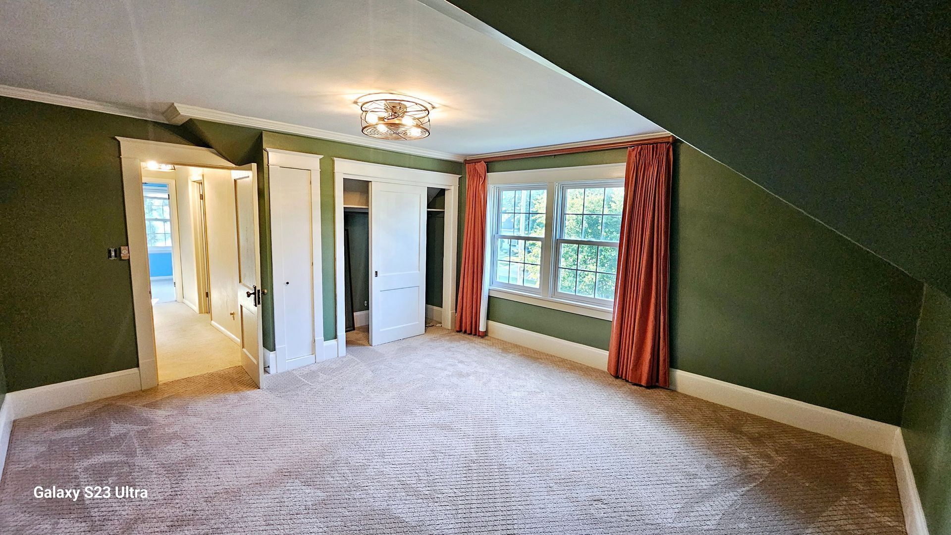 An empty bedroom with green walls and red curtains