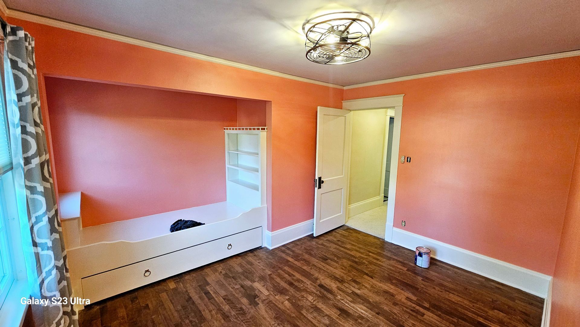 A bedroom with pink walls and a wooden floor