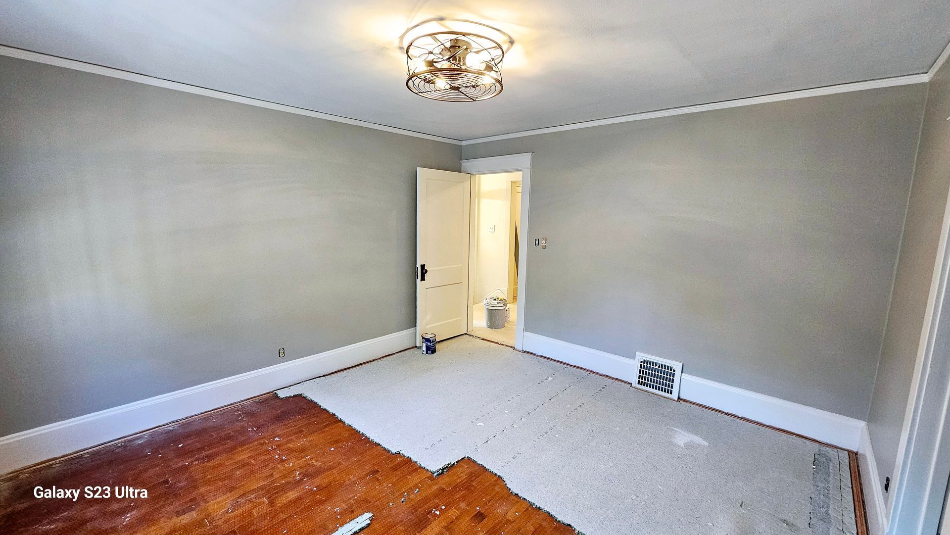 An empty room with a wooden floor and a ceiling fan