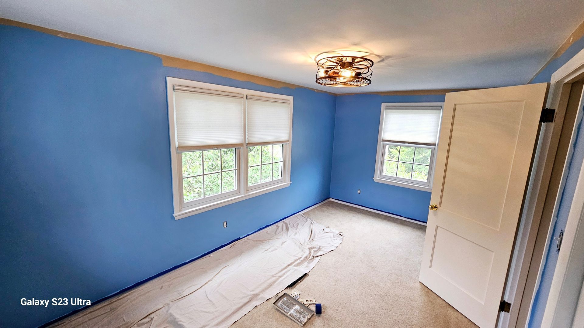 A room with blue walls and white trim is being painted