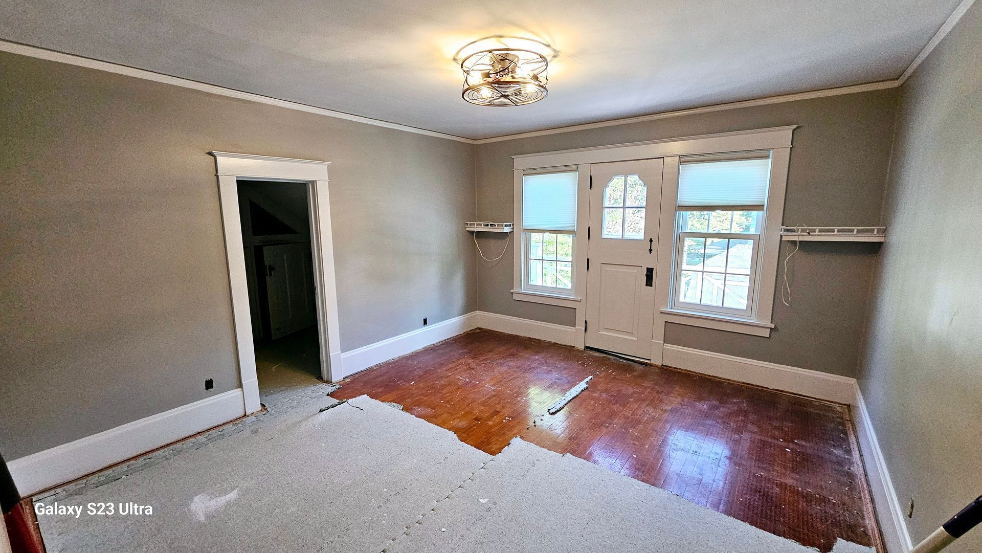 An empty living room with hardwood floors and gray walls