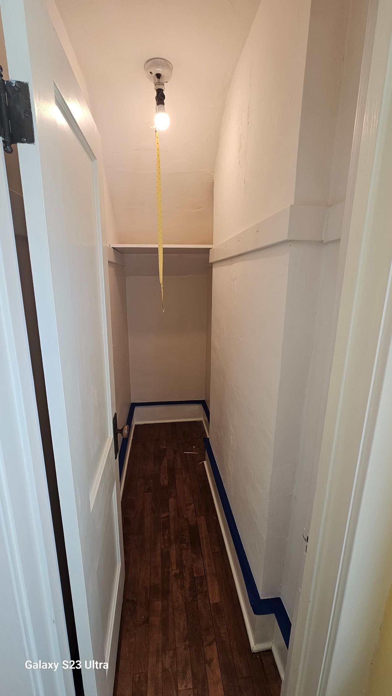 A narrow hallway with wooden floors and a light on the ceiling