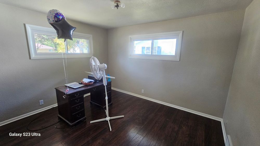 An empty room with a desk and a fan and a balloon hanging from the ceiling