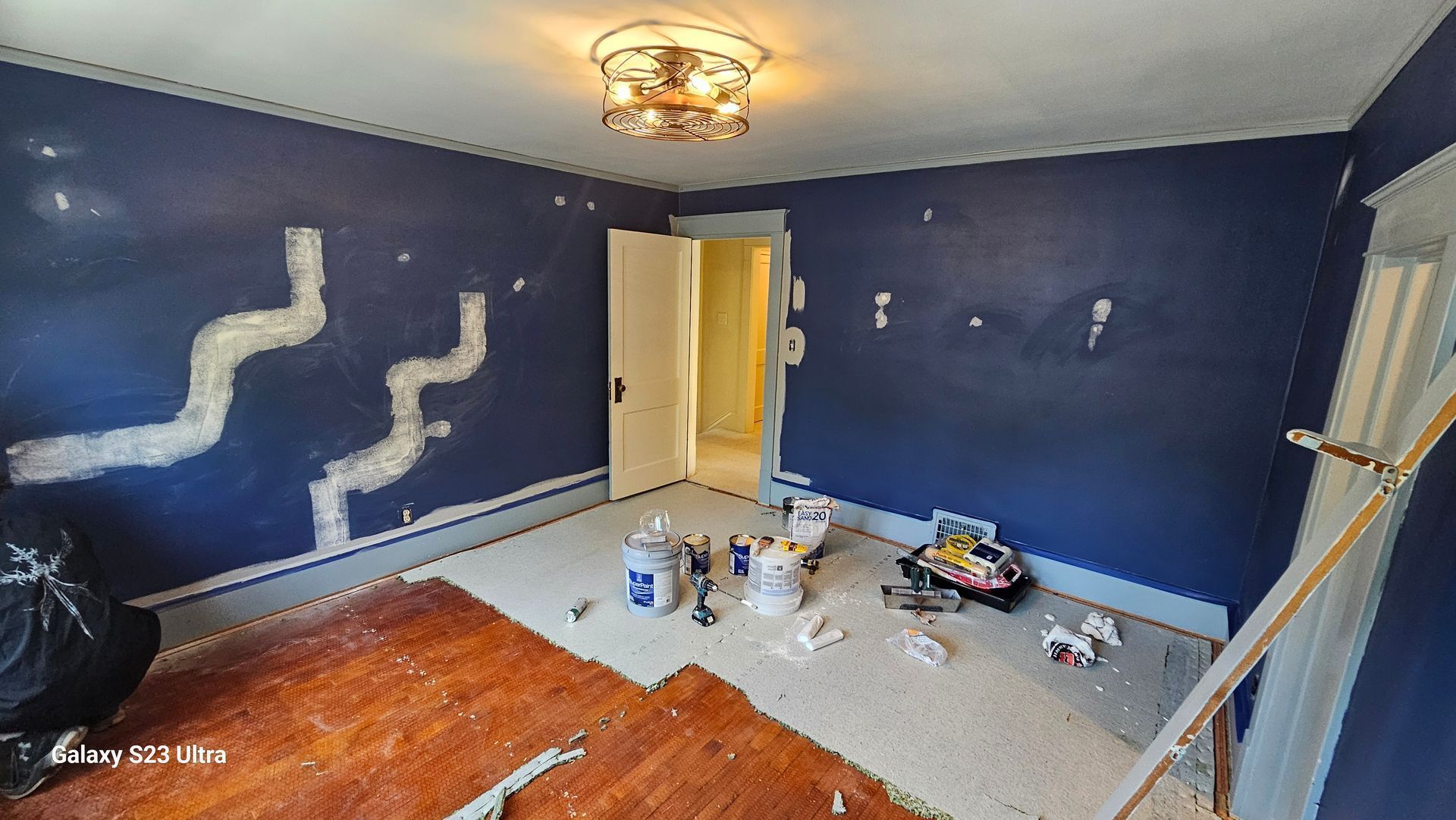 A room with blue walls and a wooden floor is being painted