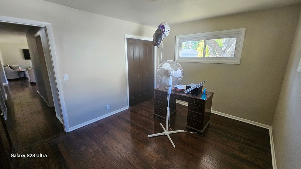 A room with a desk and a fan in it.