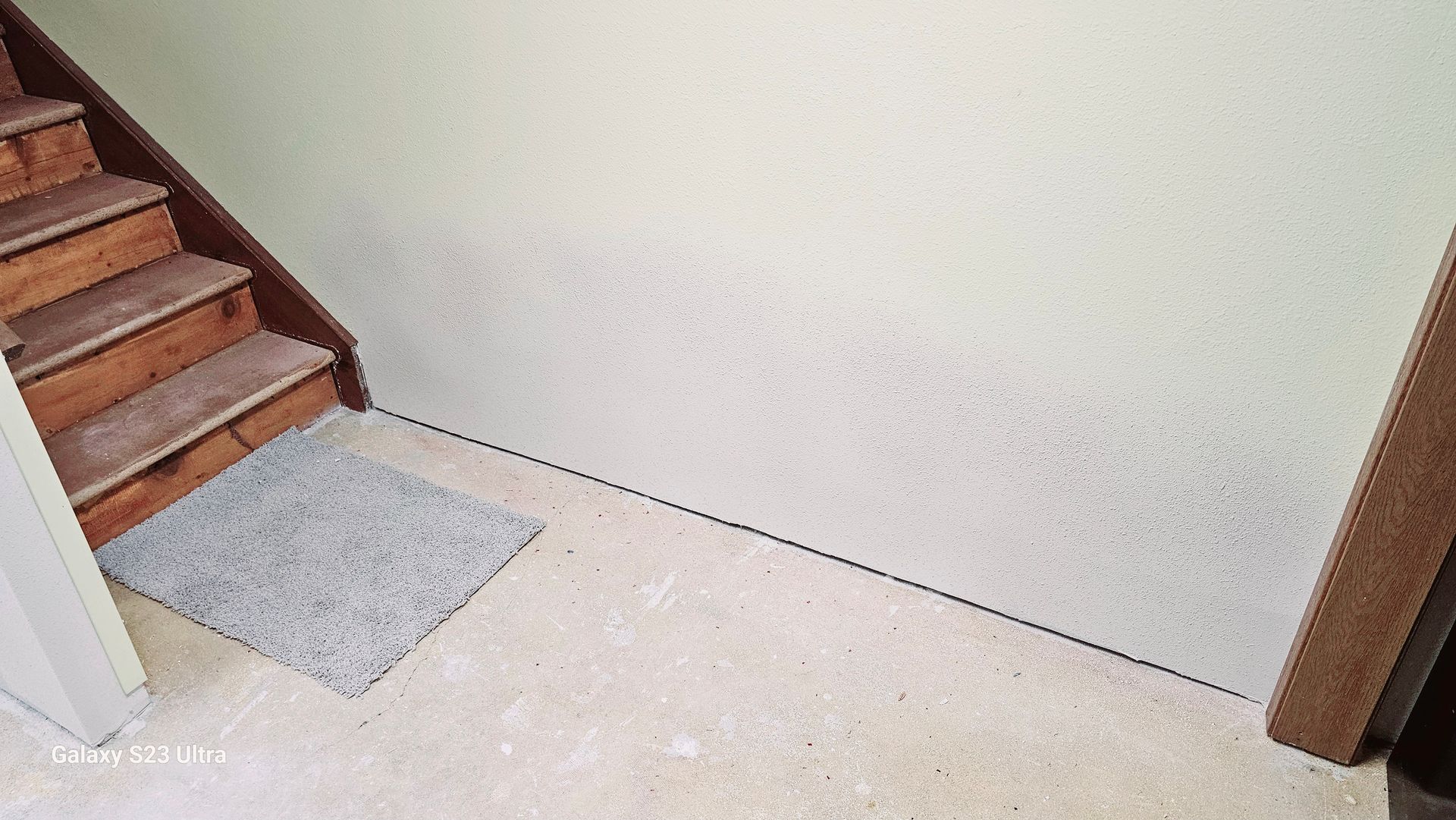 There is a rug on the floor next to the stairs