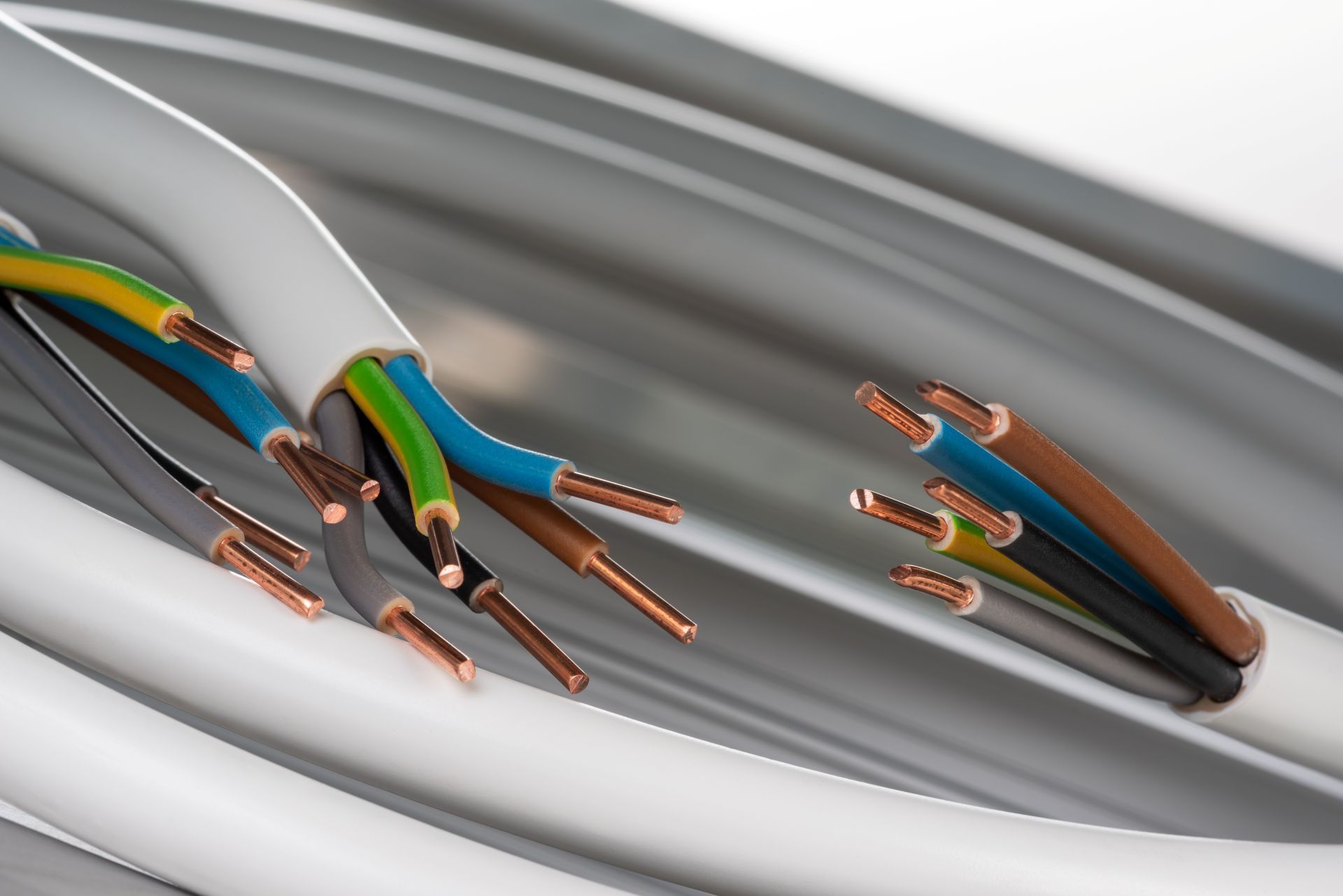 Close-up of electrical wires. Grey cable with stripped ends revealing copper conductors of various colors.