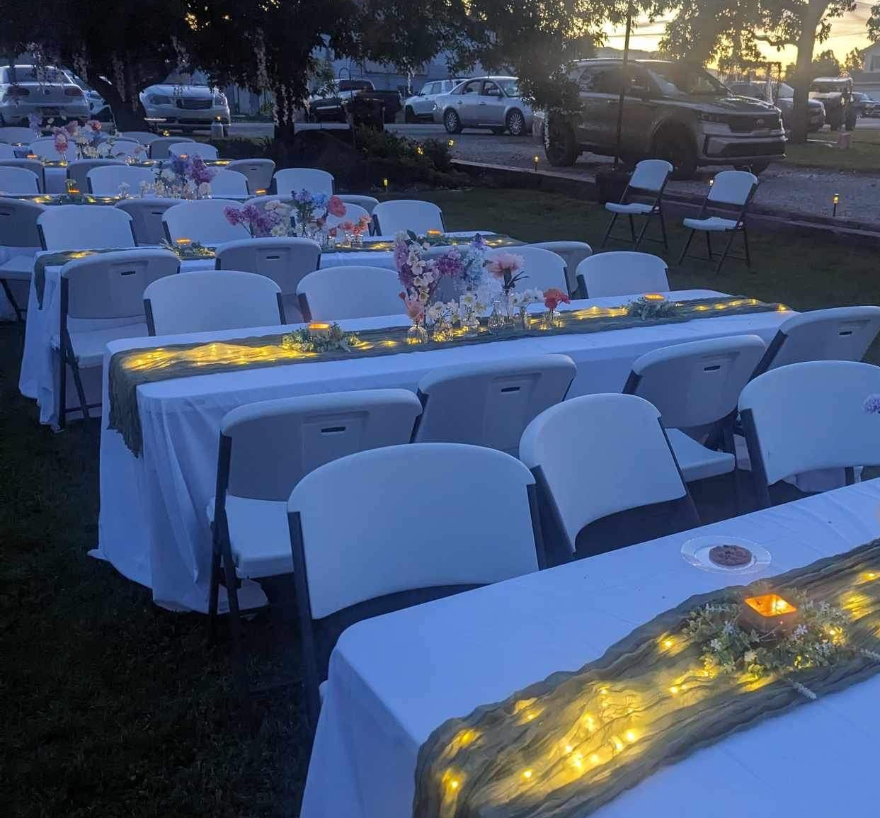 Evening outdoor event setup with rental tables and chairs