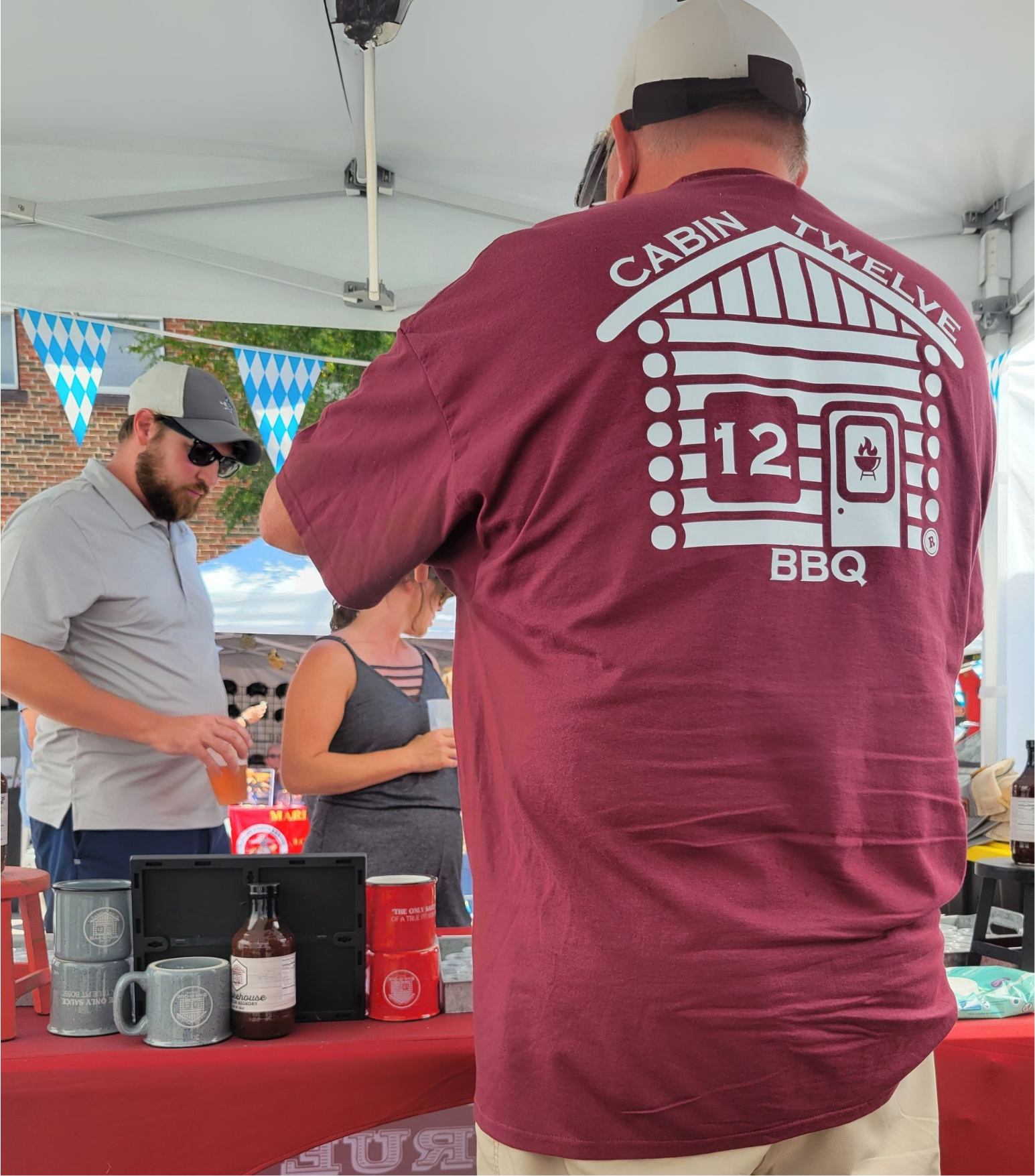 A man in a chef 's uniform is holding a box of bbq sauces.